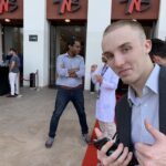 Tanner Laycock giving a thumbs-up at a conference entrance in Bucharest