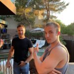 Tanner Laycock giving a thumbs-up on a pool patio with Dennis Yu